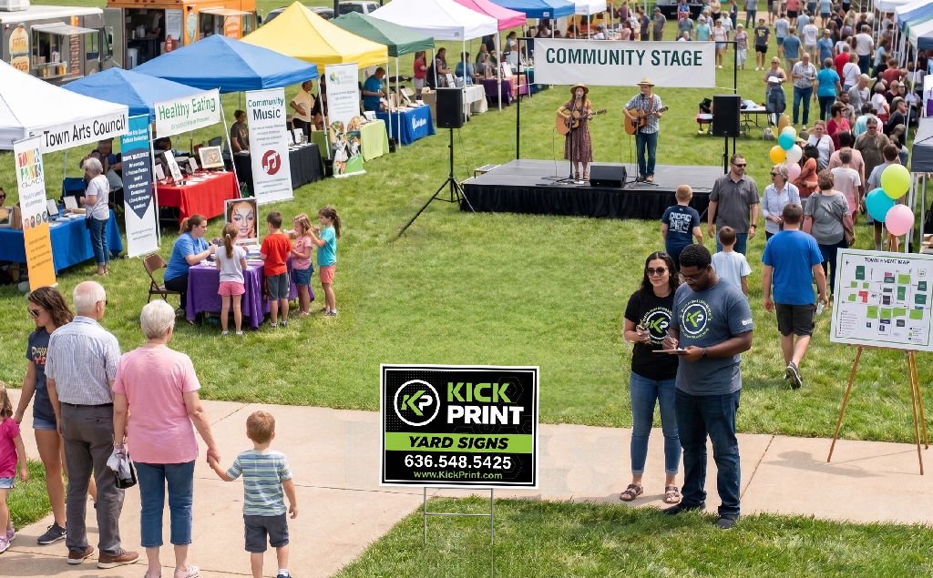 A lively outdoor community event with booths, families, and children. Two musicians perform on stage as people visit vendor tents, and a couple stands in the foreground holding drinks near an eye-catching Yard Signs display.