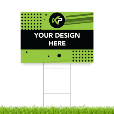 A green and black yard sign with abstract dots and lines, the KP logo at the top, and the text YOUR DESIGN HERE in bold white letters, standing on a metal frame above green grass.
