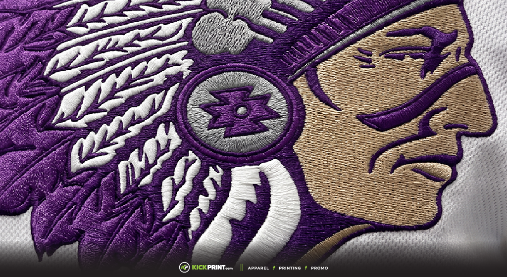 Close-up of an embroidered patch showing a Native American chief’s profile in purple, beige, and white, wearing a feathered headdress and patterned earpiece. Proudly crafted in Jackson Mississippi, the “KICK-PRINT” logo appears at the bottom.