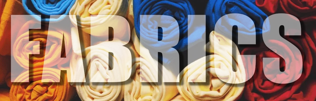 Rolls of colorful fabric are tightly packed together, forming a background with bold white text reading FABRICS overlaid across the center—perfect for showcasing our affordable screen printing services.